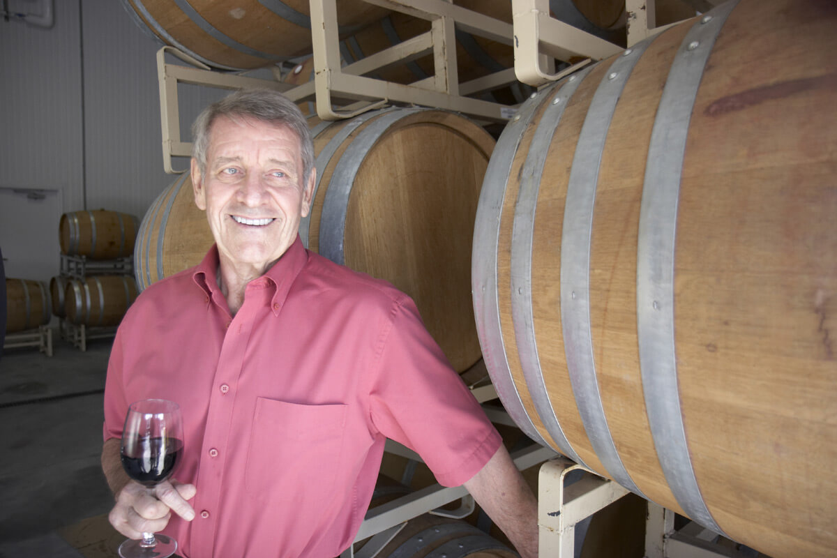 Al Scheid looking happy in front of barrels of wine
