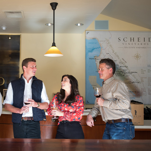 A woman and two men holding wine glasses