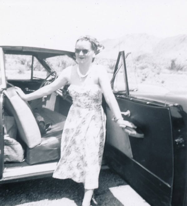 Vintage woman standing by classic car at Scheid Vineyards.