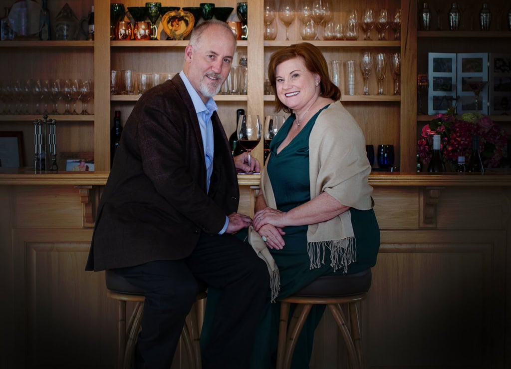 Elegant couple enjoying wine at Scheid Vineyards tasting room, showcasing wine cellar setup.