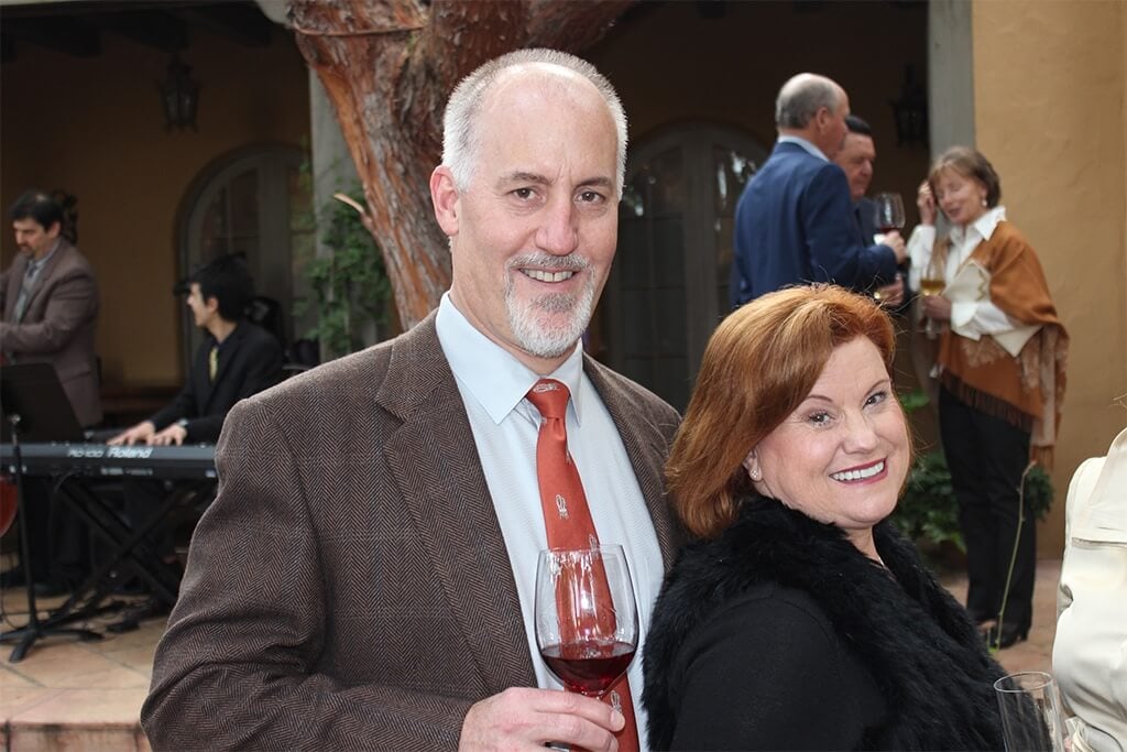 Elegant couple at Scheid Vineyards wine tasting event, enjoying red wine in a beautiful outdoor setting.