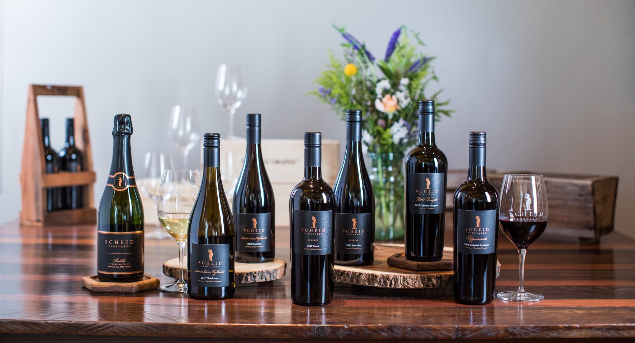 Elegant wine bottles and glasses at Scheid Vineyards showcase premium wine selection for tasting.