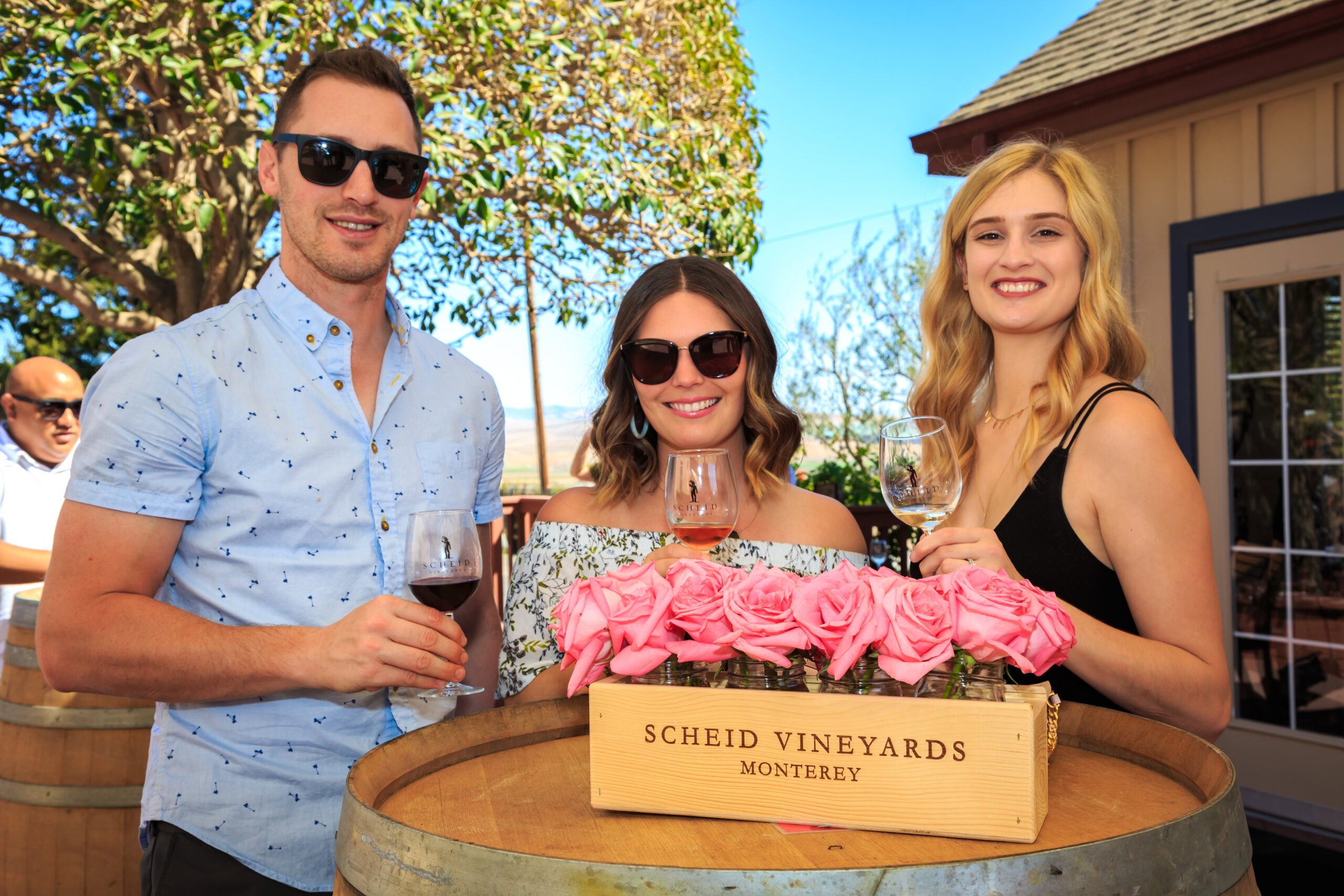 Elegant wine tasting at Scheid Vineyards Monterey in outdoor setting, smiling guests with wine glasses.